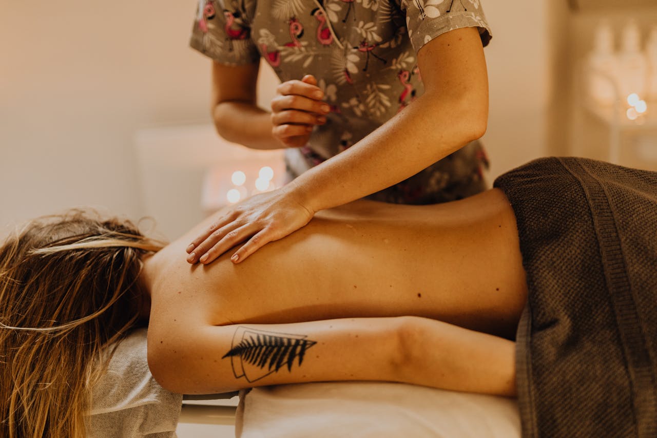 Woman receiving a relaxing back massage in a cozy spa setting, enhancing wellness and relaxation.